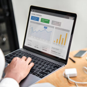 Osoba trzymająca w rękach laptopa z wyświetlonymi raportami