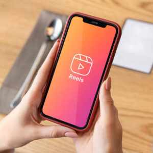 Osoba trzymająca w dłoniach telefon z logo Rolek na Instagramie