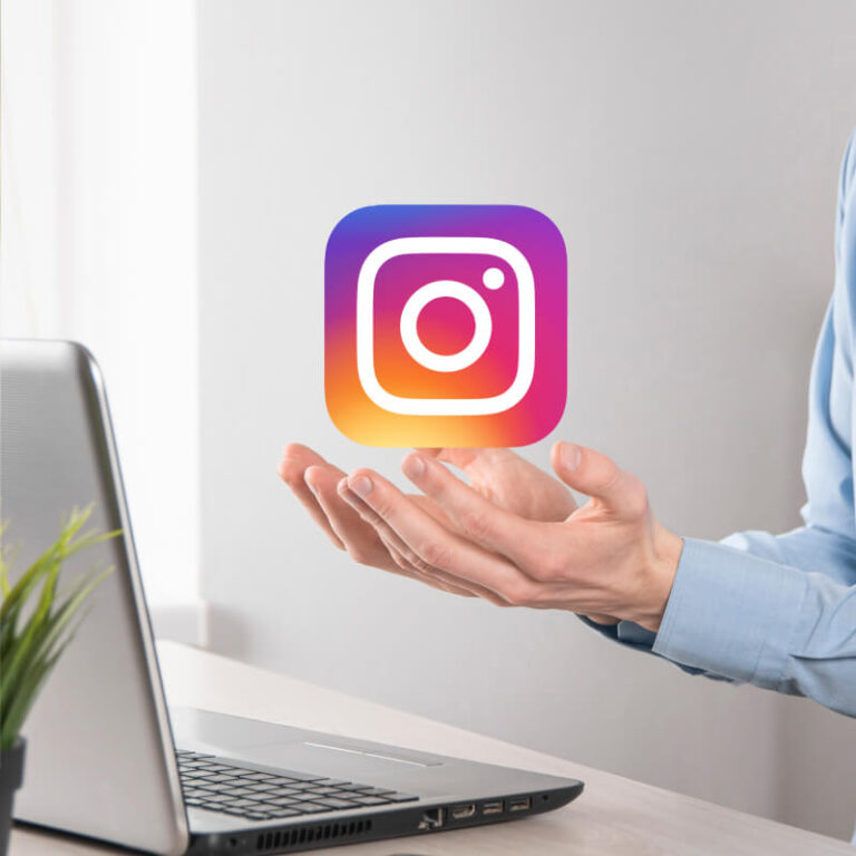 Osoba trzymająca logo aplikacji Instagram nad laptopem