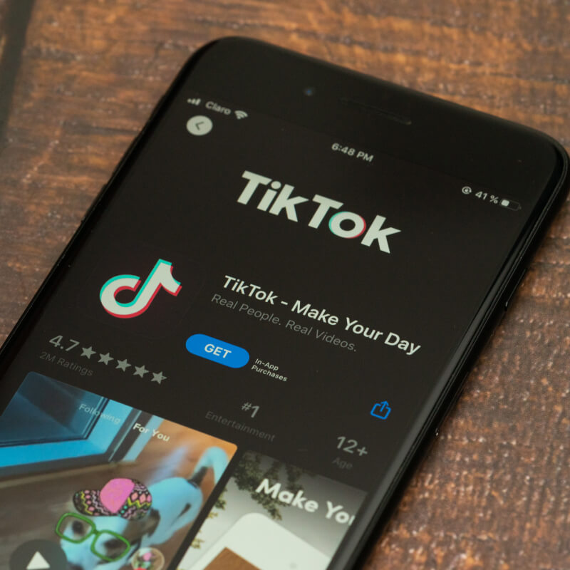Telefon z ekranem pobierania aplikacji TikTok na drewnianym tle