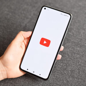 Osoba trzymająca w dłoni telefon z logo YouTube