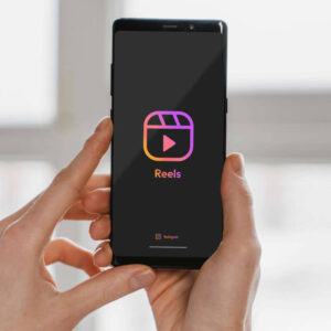 Osoba trzymająca telefon z logo Rolek aplikacji Instagram