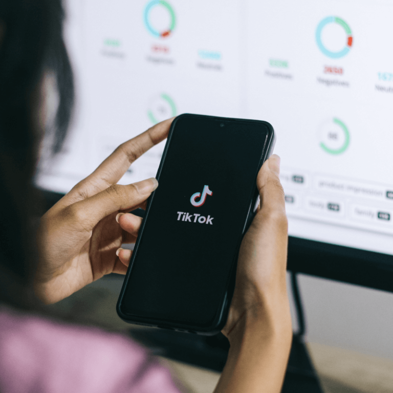 Osoba trzymająca w dłoniach telefon z logo aplikacji TikTok