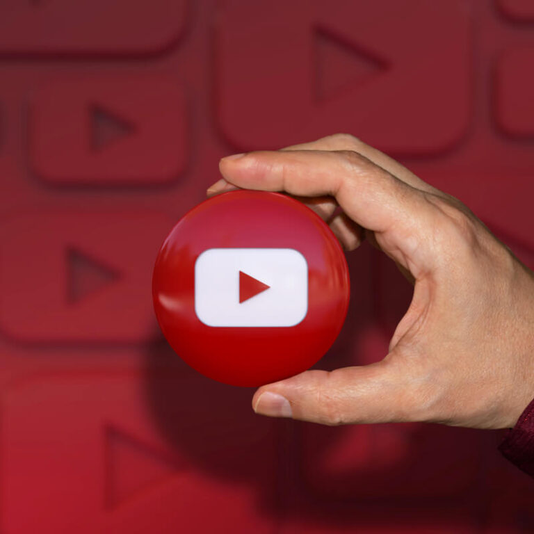 Okrągłe logo aplikacji YouTube trzymane w dłoni na na czerwonym tle
