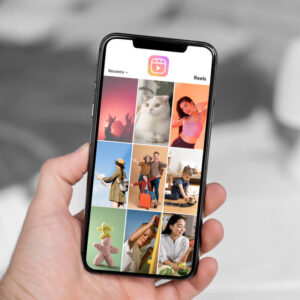 Osoba trzymająca w dłoni telefon z feedem aplikacji Instagram