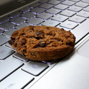 Ciasteczko reprezentujące pliki cookie leżące na klawiaturze laptopa
