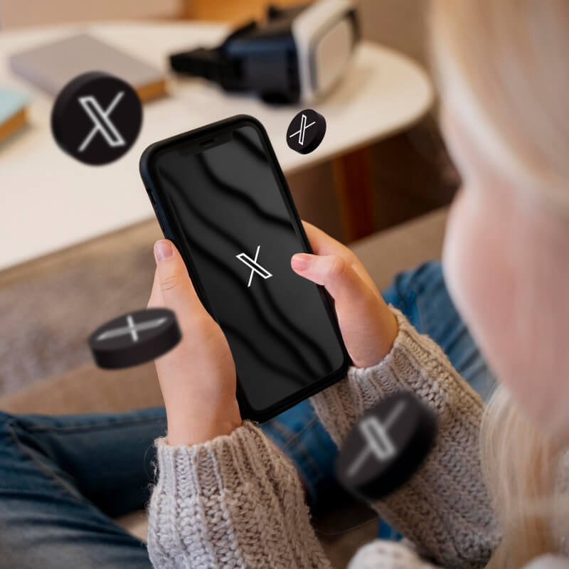 Osoba trzymająca w dłoniach telefon z logo aplikacji X